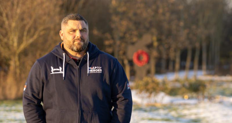 Midshot of man in Help for Heroes sweater standing outside and looking past camera