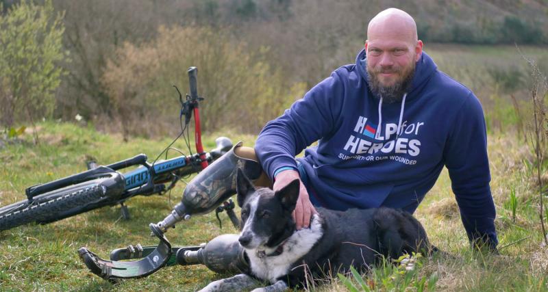 Bruce sits in field with bike and mobility aids